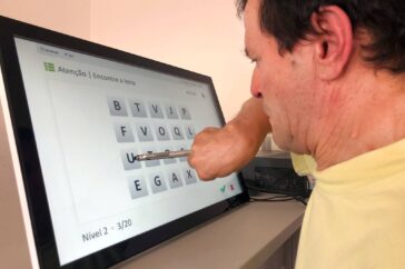 Pessoa usa a mão com uma caneta digital para escolher letras em tablet.