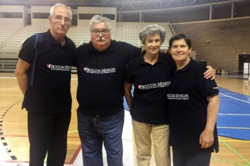Quatro pessoas lado a lado. Fotografia em pavilhão desportivo. As quatro pessoas usam camisolas com indicação: Boccia Sénior APPC.