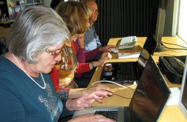 Quatro pessoas sentadas junto de vários computadores.
