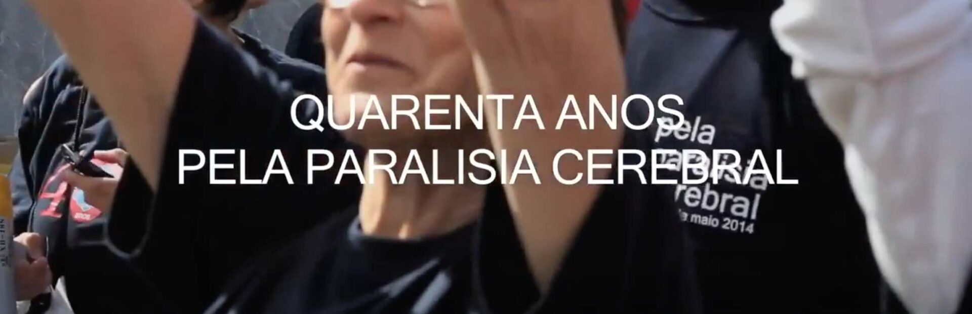 Imagem de grupo de pessoas. Pessoa de braços no ar a sorrir. Sobre a imagem, ao centro aparece a branco o texto 