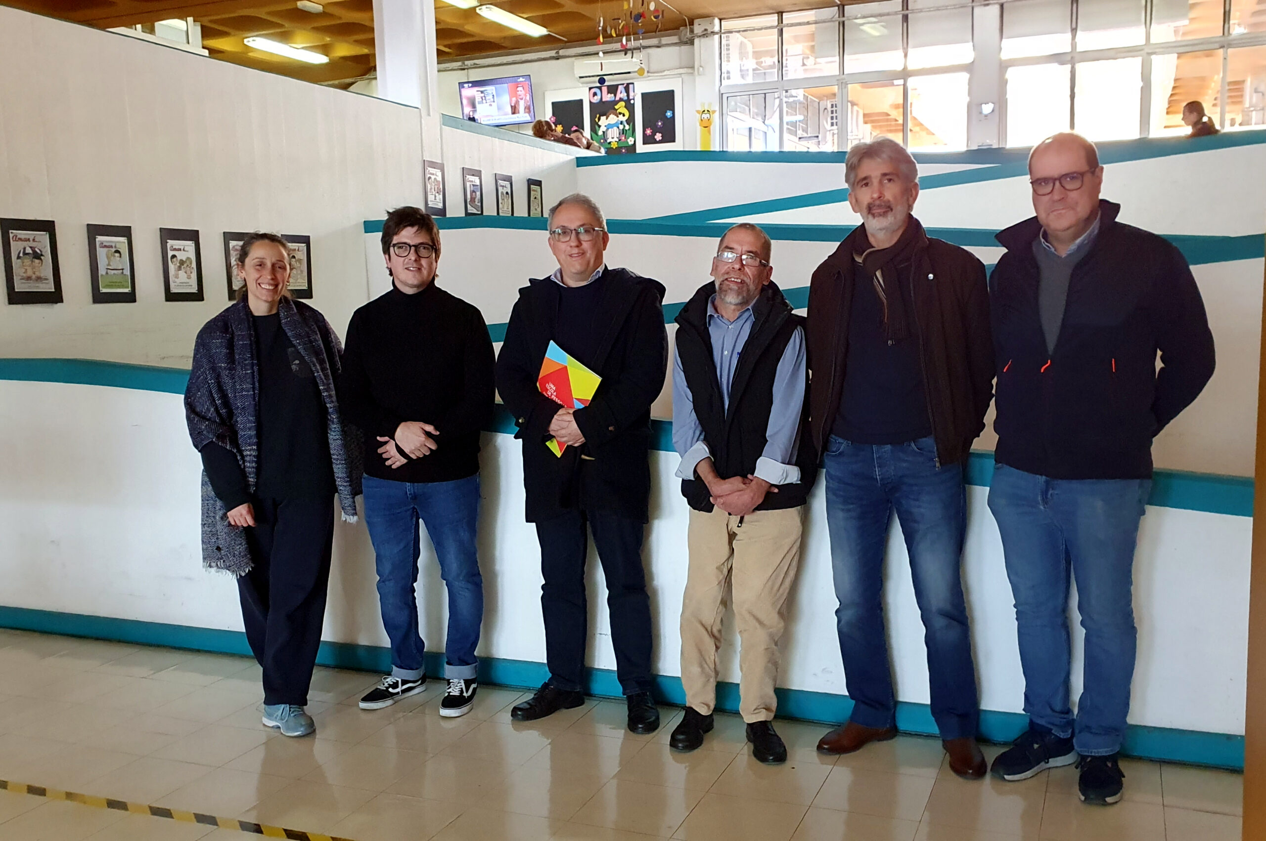 Fotografia de grupo, com seis pessoas, junto de rampa interna de acesso no Centro de Reabilitação.