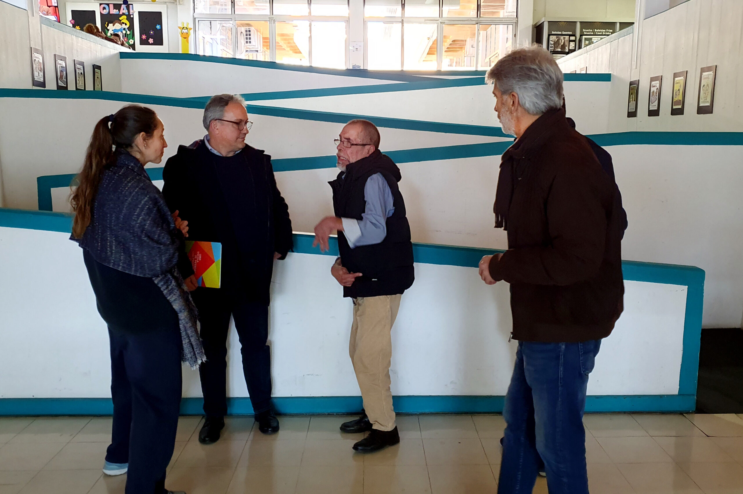 Quatro pessoas, em conversa, junto de rampa interna de acesso no Centro de Reabilitação.