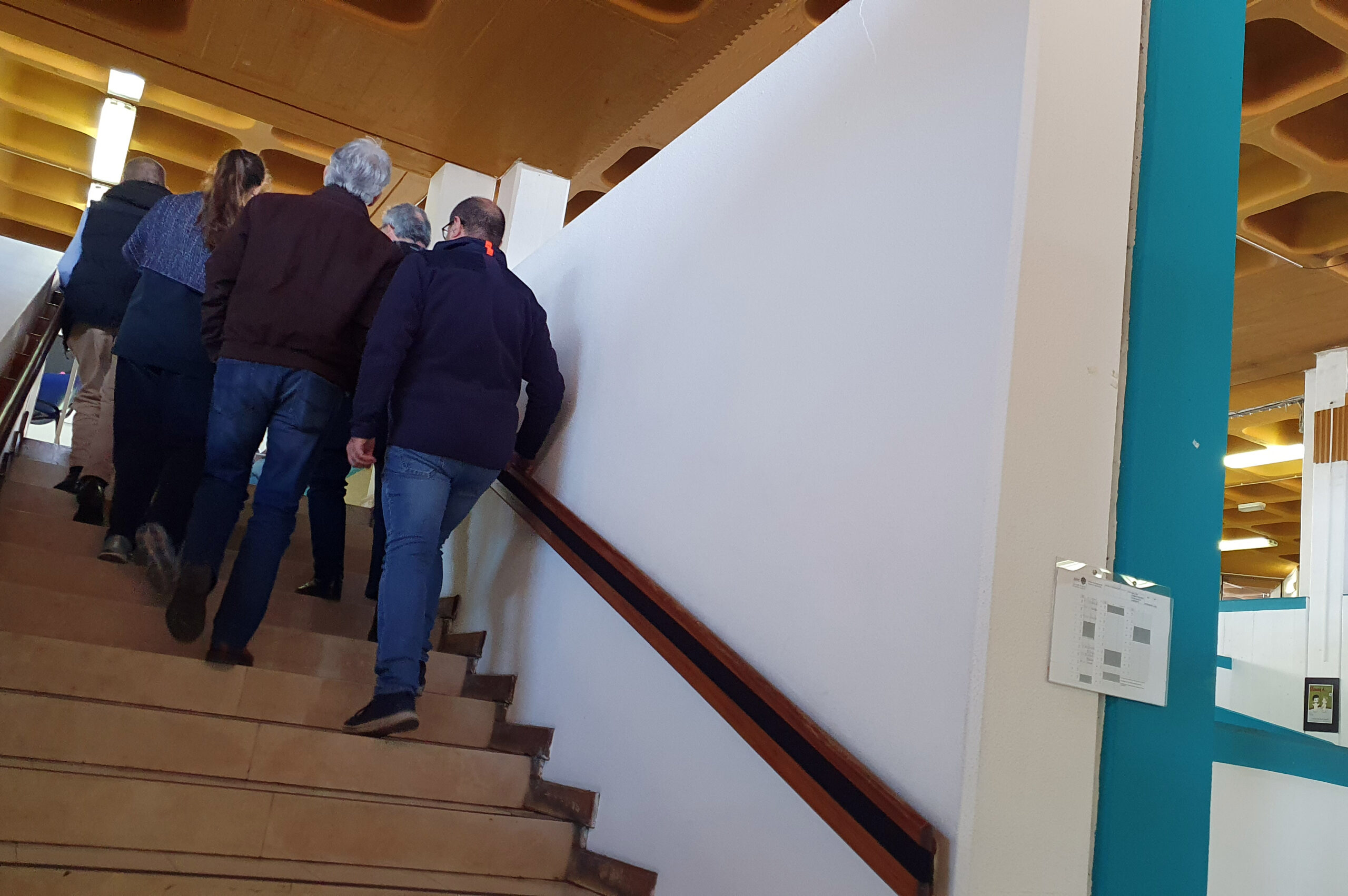 Várias pessoas, de costas, a subir umas escadas
