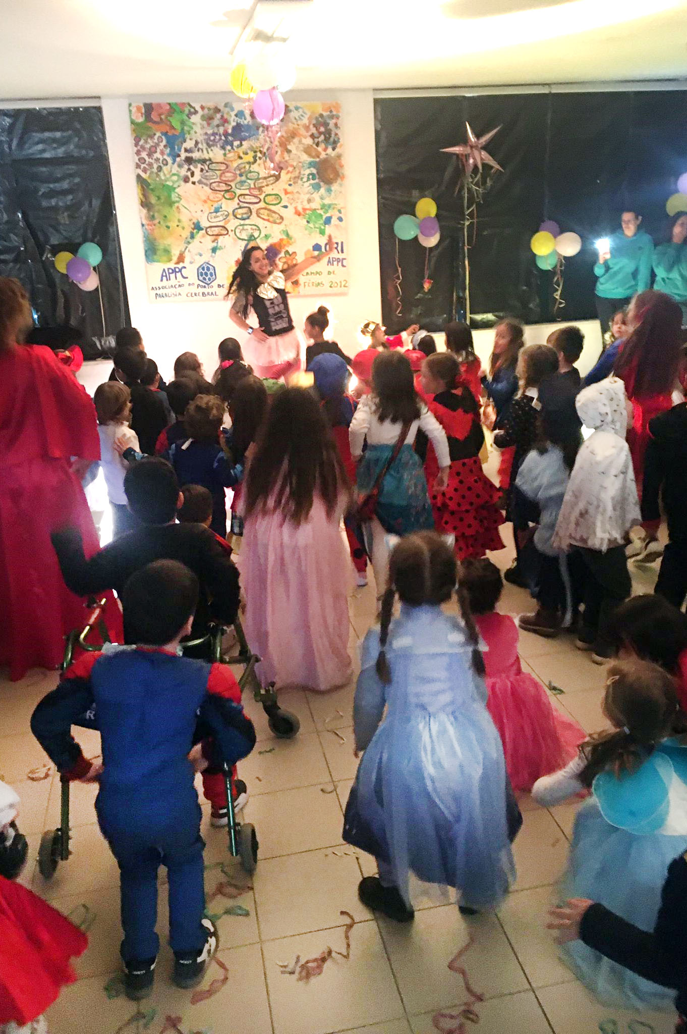 Crianças (com trajes carnavalescos) e adultos a desfilarem por uma rua da freguesia de Valbom. Os rostos das crianças foram desfocados.