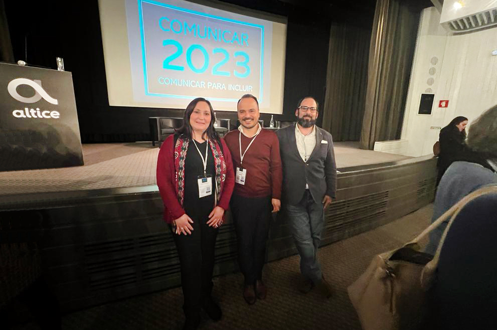 Foto de conjunto, com três pessoas, e fundo projetado da iniciativa.
