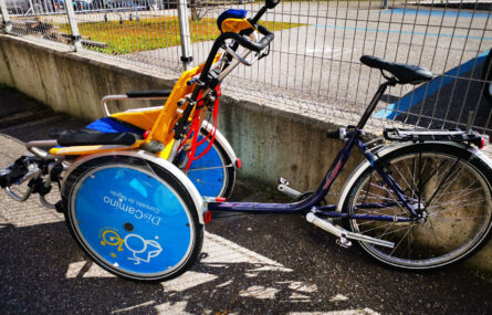 Fotografia de bicicleta adaptada junto de um gradeamento.