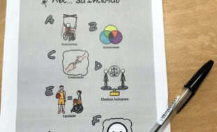 Fotografia de documento “ABC... da Inclusão” pousado em cima de mesa castanha. Na diagonal, também na mesa, está uma esferográfica.
