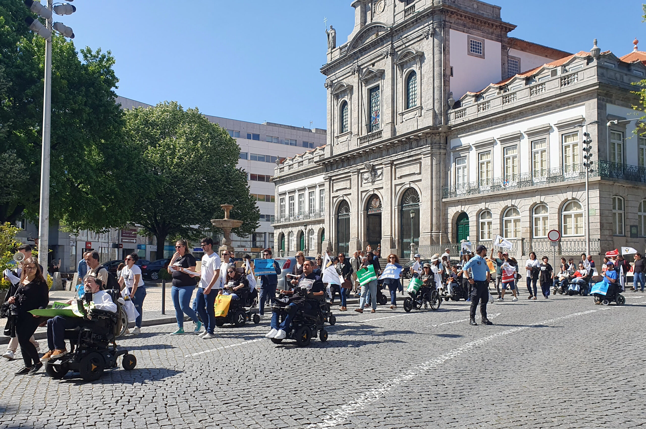 Perspetiva de parte da Marcha em rua de paralelos mesmo junto da Câmara Municipal do Porto. Um elemento da PSP assegura a segurança e o respeito pelo trajeto definido.