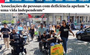 Cópia parcial de página do site do Jornal de Notícias (link na publicação). Título: Associações de pessoas com deficiência apelam a uma vida independente. Mais abaixo, fotografia de várias pessoas em manifestação, na rua. À frente do grupo seguem três pessoas em cadeiras de rodas. Uma delas usa um megafone e leva pendurado, na cadeira, um cartaz que diz: A minha vida não é um projeto piloto.