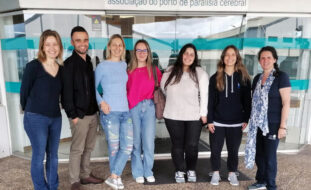 Grupo de sete pessoas junto à entrada principal do Centro de Reabilitação da APPC.