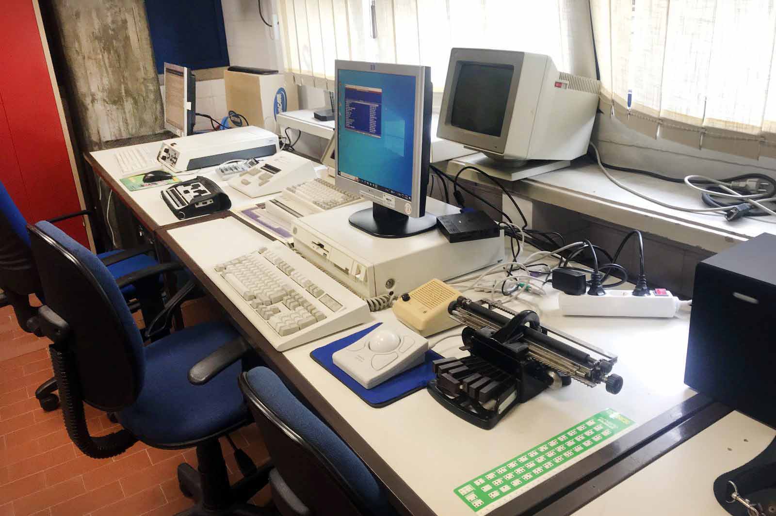 Fotografia de inúmeras tecnologias de apoio dispersas em cima de duas mesas.