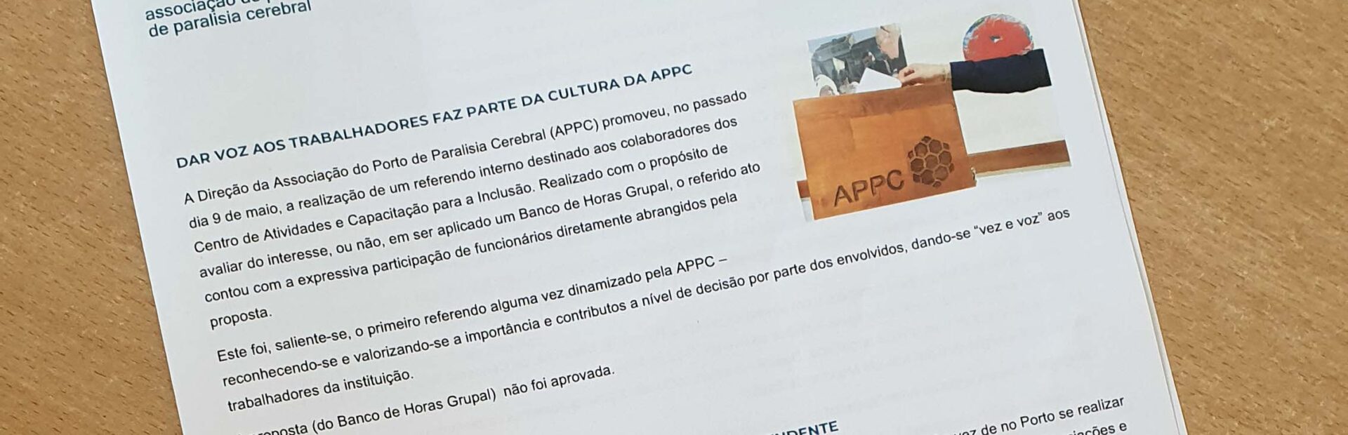 Fotografia da newsletter pousada em cima de uma mesa. Vê-se a primeira página e as duas notícias em destaque.