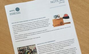 Fotografia da newsletter pousada em cima de uma mesa. Vê-se a primeira página e as duas notícias em destaque.