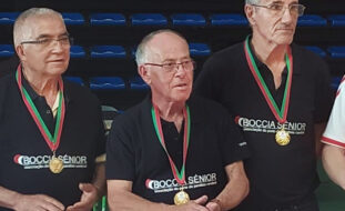 Fotografia de três dos elementos da Equipa de Boccia Sénior da “Villa Urbana” de Valbom, da APPC. São três pessoas, do sexo masculino, com medalhas ao peito e a usarem camisola azul (escuro) com a inscrição Boccia Sénior Associação do Porto de Paralisia Cerebral.