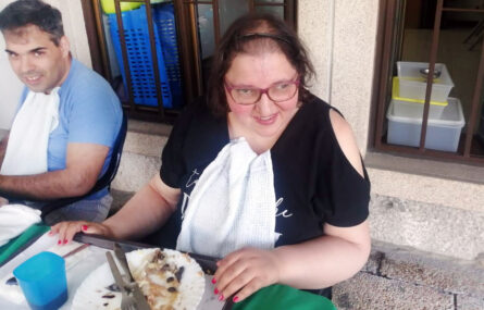 Fotografia de duas pessoas sentadas à mesa. Vê-se um prato já quase vazio e com alguns restos de comida.