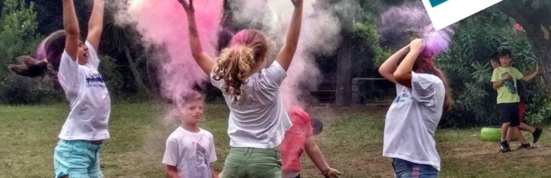 Imagem de divulgação de Voluntariado para acompanhamento nas atividades de verão (em julho, agosto e setembro) do Centro de Atividades de Tempos Livres. Fotografia de cinco crianças em jardim a lançarem pó colorido para o ar. Ao fundo, junto das árvores, estão mais duas crianças. Na parte superior da imagem, uma abelha, um coração encarnado e um losango a comporem o símbolo do Voluntariado da APPC. Em baixo, em letras brancas sobre fundo azul, a frase “Comprometa-se com uma causa”, a indicação do sítio da APPC e as respetivas redes sociais.