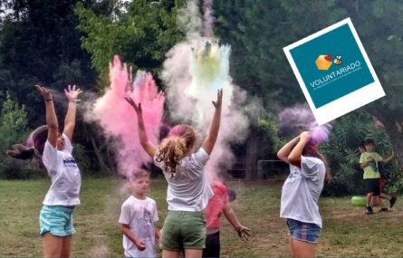Imagem de divulgação de Voluntariado para acompanhamento nas atividades de verão (em julho, agosto e setembro) do Centro de Atividades de Tempos Livres. Fotografia de cinco crianças em jardim a lançarem pó colorido para o ar. Ao fundo, junto das árvores, estão mais duas crianças. Na parte superior da imagem, uma abelha, um coração encarnado e um losango a comporem o símbolo do Voluntariado da APPC. Em baixo, em letras brancas sobre fundo azul, a frase “Comprometa-se com uma causa”, a indicação do sítio da APPC e as respetivas redes sociais.