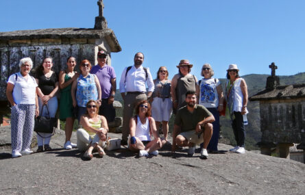 Fotografia de 13 pessoas junto de espigueiros do Soajo. Ao fundo, montes e céu azul.