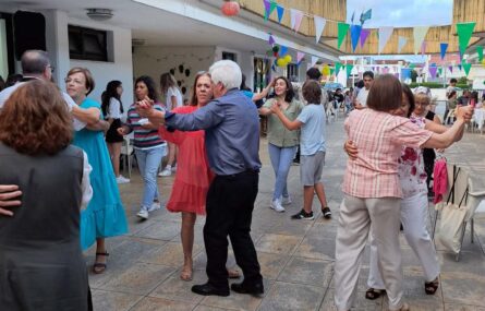 Perto de duas dezenas de pessoas dançam em pares.
