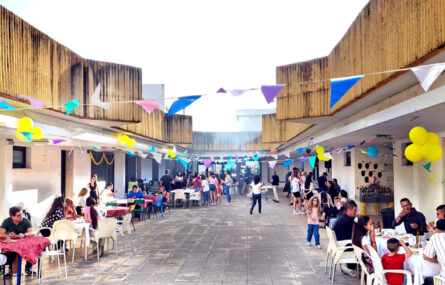 Imagem da zona de entrada, exterior, da Villa Urbana de Valbom. Mais de duas dezenas de pessoas estão em convívio – a maioria sentada à mesa, a conversar e a comer.