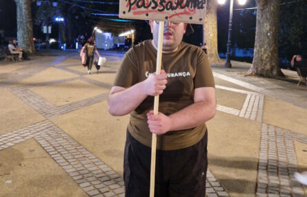 Fotografia de uma pessoa a segurar duas mensagens de reivindicação.