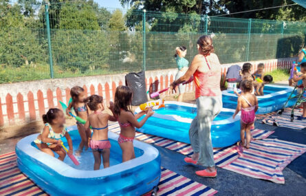 Perto de uma dezena de crianças dentro e fora de três pequenas piscinas (insufláveis, de jardim). Algumas mantas espalhadas pelo chão.