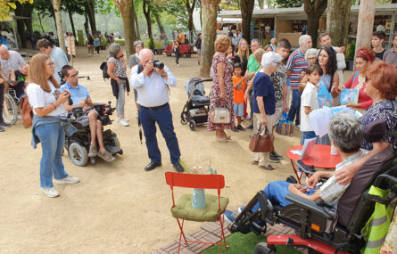 Fotografia em perspetiva de várias pessoas em espaço aberto na Feira do Livro do Porto, nos jardins do Palácio de Cristal. A maioria assiste e ouve as palavras de António Magalhães. Ao centro da imagem uma pessoa faz fotografias.
