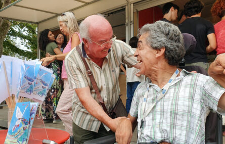 António Magalhães ao lado de um leitor que acompanhou a apresentação do livro. Estão ambos sorridentes. Ao fundo da imagem pessoas a adquirir livro no stand da editora.