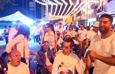 Fotografia de pessoas numa das ruas com animação para a Noite Branca de Gondomar. Em primeiro plano alguns dos elementos da comitiva da APPC. Mais ao fundo aparecem mais pessoas. A rua tem, suspensos, centenas de enfeites brancos em formato de estrela.
