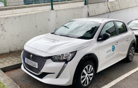 Fotografia, em perspetiva diagonal, de um carro estacionado. A viatura é de marca Peugeot e de cor branca. Na porta lateral, do condutor, vê-se o logótipo da APPC e a designação da instituição: Associação do Porto de Paralisia Cerebral. Atrás do referido carro ainda se consegue ver um pouco de outra viatura.