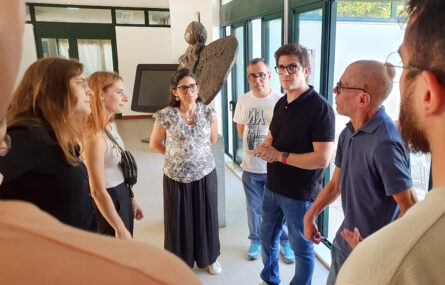 Fotografia de momento durante a receção na “Villa Urbana” de Valbom. Vários jovens conversam com representantes da APPC. Vê-se ainda, mais ao fundo, uma escultura e um ecrã gigante.