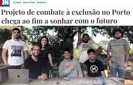Cópia parcial de notícia publicada no sítio do Jornal de Notícias. Em cima barra com logótipo do JN. Depois título da notícia “Projeto de combate à exclusão no Porto chega ao fim a sonhar com o futuro” e logo abaixo fotografia de sete pessoas (de pé e sentadas) junto da uma mesa de pedra de um jardim. Em cima da mesa está pousado um computador portátil. Atrás das pessoas uma árvore e alguns arbustos.