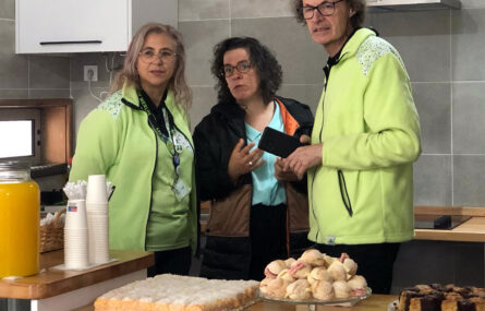 Naquela que aparenta ser a zona da cozinha de um apartamento, estão três pessoas a conversar. Em primeiro plano, numa bancada, estão alguns aperitivos e doces. Mais à esquerda vê-se ainda um jarro com sumo de laranja.