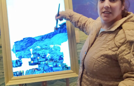 Uma pessoa utiliza um pincel num quadro interativo que simula uma pintura (toda em tons de azul).