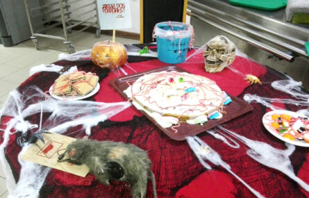 Plano aproximado de uma mesa com várias sobremesas e decoração alusiva ao Halloween.