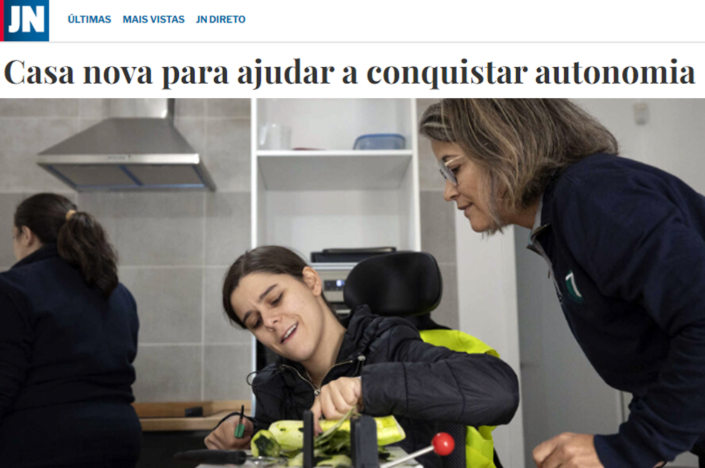 Captura de ecrã de página do sítio do “Jornal de Notícias”. Notícia com o título “Casa nova para ajudar a conquistar autonomia” acompanhada de fotografia na qual aparecem três pessoas – ao centro, sentada em cadeira de rodas, uma pessoa corta parcialmente uma curgete; à direita outra pessoa olha atentamente; ao fundo da imagem algum equipamento de cozinha e uma outra pessoa, mas de costas.