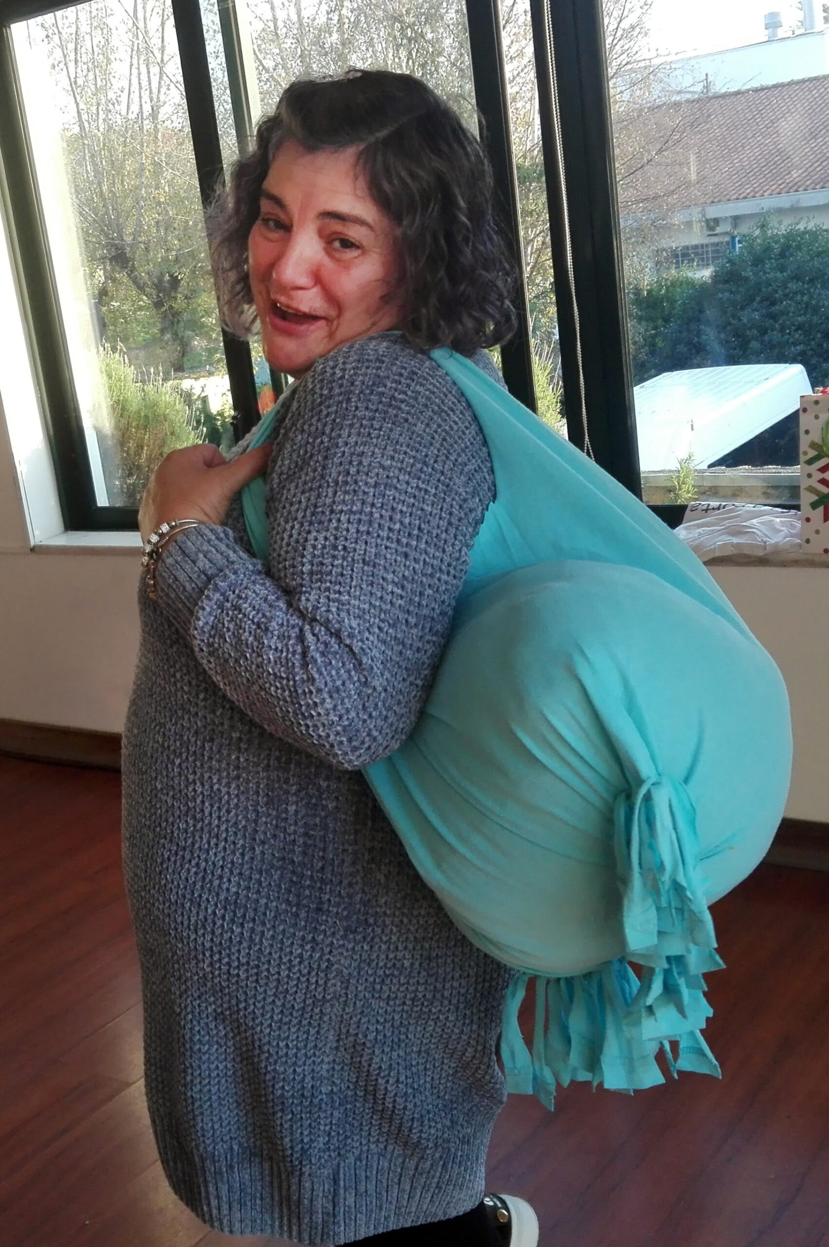 Uma pessoa, de perfil, com um saco feito de material reciclado às costas.