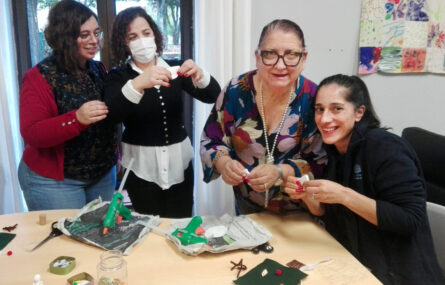 Quatro pessoas, sorridentes, junto de uma mesa com diversos materiais a serem reciclados.