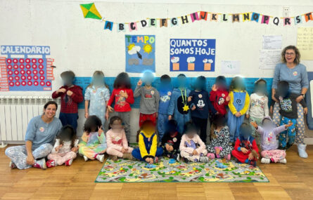 Grupo de duas dezenas de crianças, todas a usar pijama. Na fotografia aparecem ladeadas por duas pessoas adultas, também a usar pijama. Todos os rostos das crianças foram desfocados.