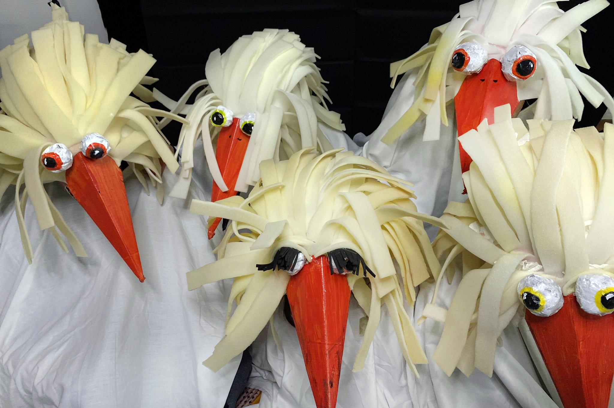Cinco pessoas caracterizadas com máscara e roupa a simular cegonhas.