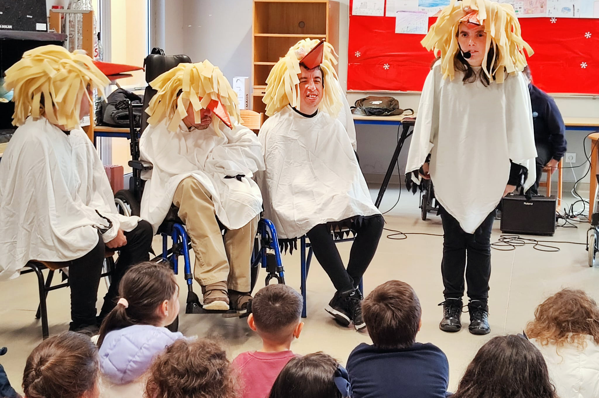 Quatro elementos do Era uma vez Teatro atuam, caracterizados de cegonhas, para grupo de crianças (que se encontra de costas em primeiro plano).
