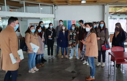 Grupo de pessoas em visita a espaço desportivo interior. Todas usam máscara de proteção individual. Ao fundo, junto da parede, alguns cacifos.