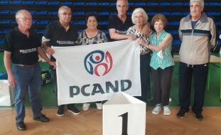 Grupo de sete pessoas. Algumas seguram uma bandeira com a inscrição PCAND.