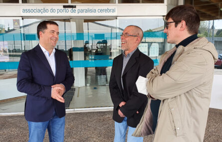 Três pessoas, com ar sorridente, junto da entrada principal do Centro de Reabilitação da APPC.