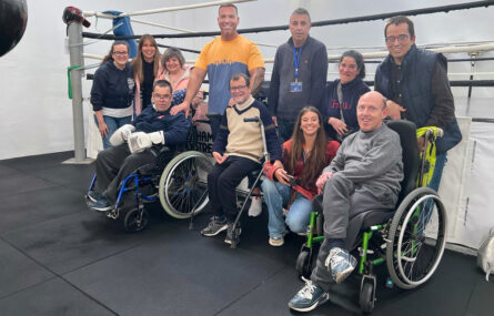 Fotografia de um grupo de 11 pessoas. Estão junto de um ringue de boxe.
