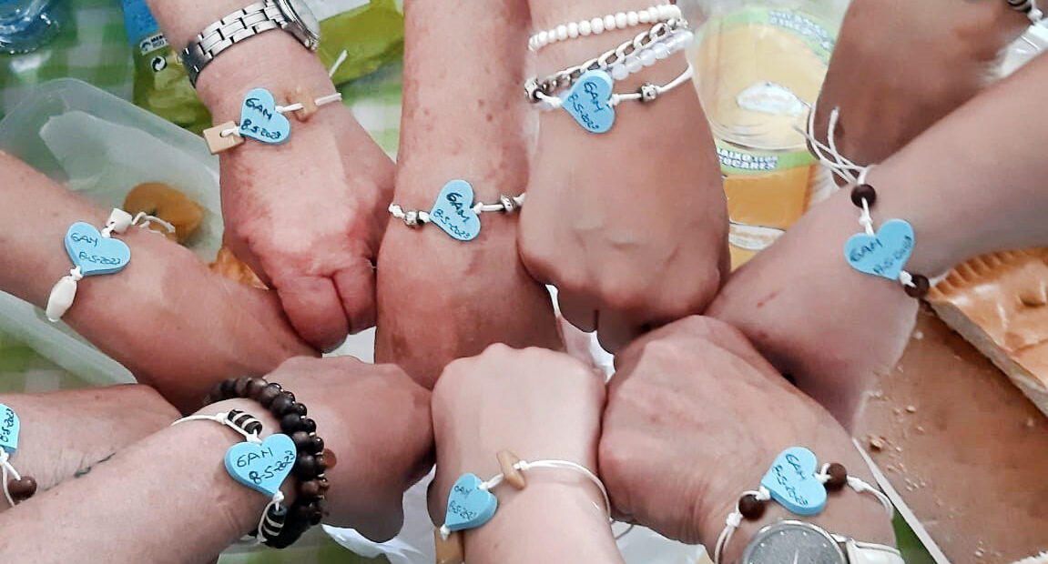 Fotografia de um conjunto de mãos todas com uma pulseira com um coração azul e vários