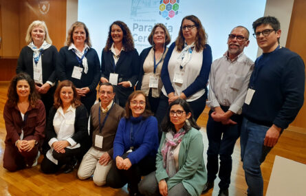 Grupo de 12 pessoas sorridentes. Ao fundo projeção em ecrã.