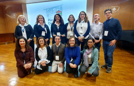 Grupo de 12 pessoas sorridentes. Ao fundo projeção em ecrã.