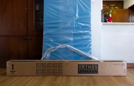 Fotografia de equipamento ortopédico encostado junto de uma parede (com um armário).