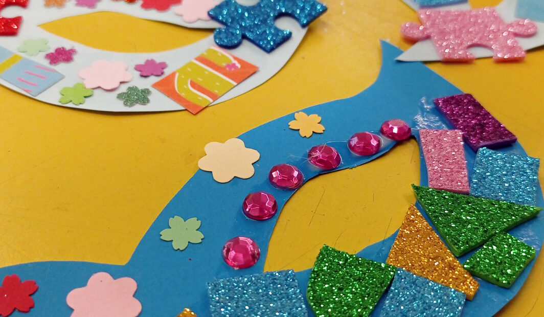 Plano aproximado de uma mesa com vários trabalhos e colagens coloridas.
